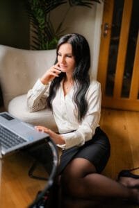 Businesswoman working on a laptop while sitting comfortably during a professional business photoshoot, ideal for relaxed and authentic branding.
