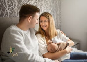 Mom breastfeeding her newborn baby while smiling at dad during a lifestyle newborn photoshoot at home.