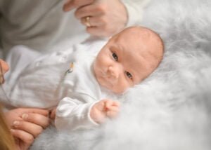 A newborn baby lying awake on a soft fluffy blanket during a newborn photoshoot at home.