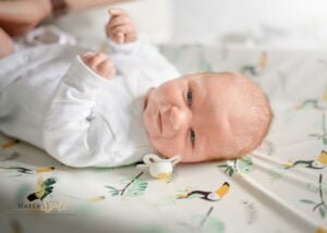Newborn lying awake on a patterned changing pad during a newborn photoshoot at home