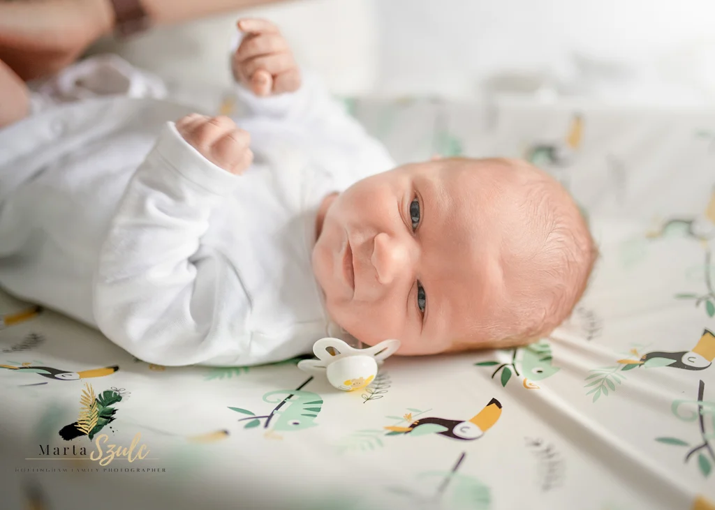 Newborn lying awake on a patterned changing pad during a newborn photoshoot at home