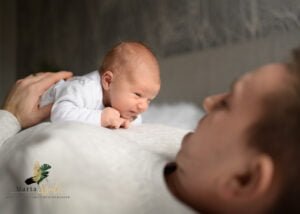 Newborn lying on dad’s chest during tummy time in a newborn photoshoot at home.