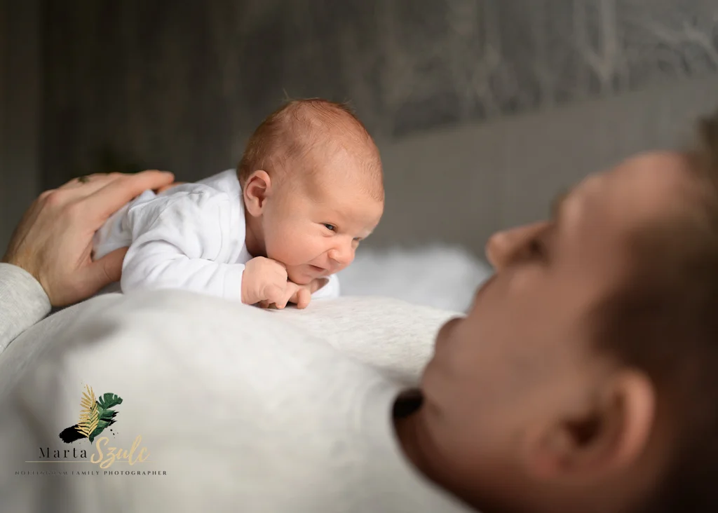 Newborn lying on dad’s chest during tummy time in a newborn photoshoot at home.