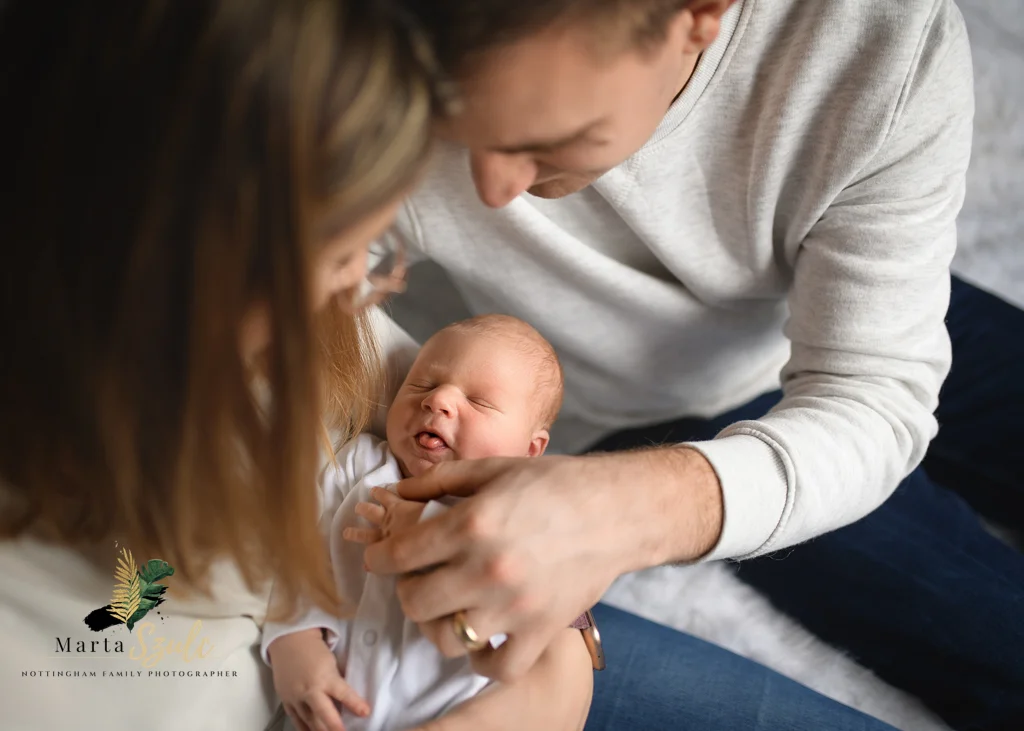 Parents smiling at their newborn baby during a relaxed newborn photoshoot at hom