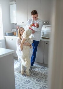 Family cuddling with their newborn baby and dog in the kitchen during a newborn photoshoot at home.
