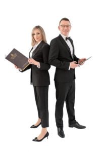 Male and female professionals in suits posing back-to-back during a professional business photoshoot with white backgrounds.