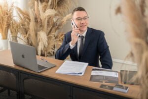 Male professional working at a desk with a laptop and documents during a professional business photoshoot in an office setting.