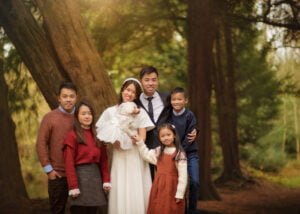 Couple posing with their family under a tree during a pre-wedding photoshoot at Elvaston Castle.