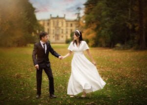 Couple holding hands in a lush garden during their pre-wedding photoshoot at Elvaston Castle, surrounded by autumn foliage.