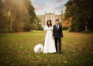 Couple walking with their dog in front of Elvaston Castle during a pre-wedding photoshoot.