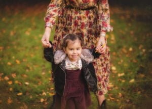 Smiling child holding parent’s hands during family outdoor photography at Colliers Wood.