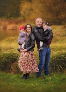 Family standing by the pond with autumn foliage in Colliers Wood.