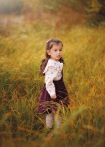 Child standing in golden grass during a family outdoor photography session in Nottingham.
