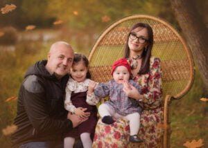 Family sitting outdoors surrounded by autumn leaves during a photography session in Nottingham.