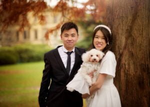 Couple posing with their dog during a pre-wedding photoshoot at Elvaston Castle, framed by vibrant autumn leaves.