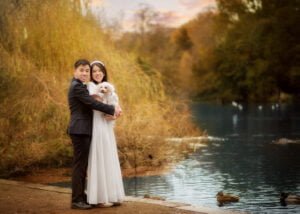 Couple embracing by the lakeside during a pre-wedding photoshoot at Elvaston Castle, with autumn colors reflecting in the water.
