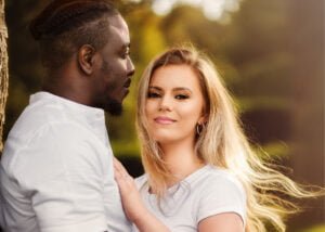 Engaged couple sharing a tender moment outdoors during their engagement photoshoot, with natural sunlight enhancing the scene.