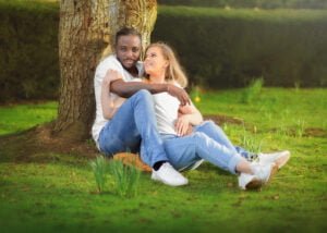 Engaged couple sitting under a tree, sharing an intimate and relaxed moment during their engagement photoshoot.