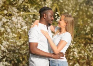 Engaged couple embracing amidst spring blossoms during their engagement photoshoot.