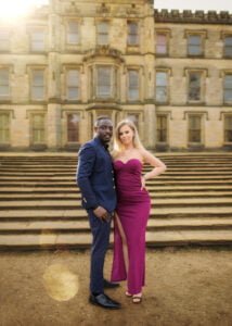 Engaged couple posing confidently in front of a historic building during their elegant engagement photoshoot.