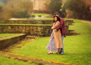A couple embracing outdoors during a professional outdoor photoshoot for women, with a castle in the background.