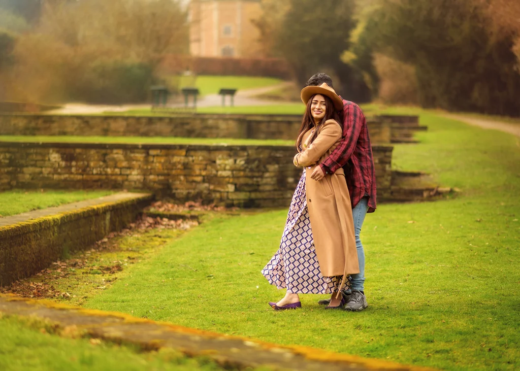 A couple embracing outdoors during a professional outdoor photoshoot for women, with a castle in the background.