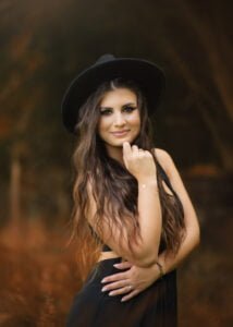 Outdoor female portrait photography with a stylish woman in a black dress and a chic black hat.