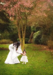 A mother and child enjoying tender moments under a blossoming tree during a Nottingham Mother and Child Photoshoot.