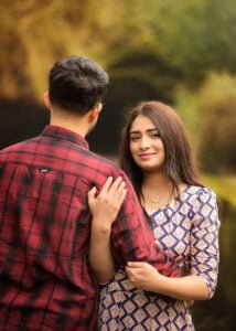 A couple posing together during an outdoor photoshoot, highlighting the woman’s patterned dress and the relaxed atmosphere.