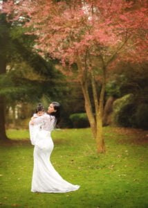 A tender moment of a mother holding her baby under a blossoming cherry tree during a Nottingham Mother and Child Photoshoot.