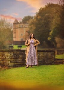 Woman in a long patterned dress posing confidently near a historic building during her outdoor photoshoot for women.