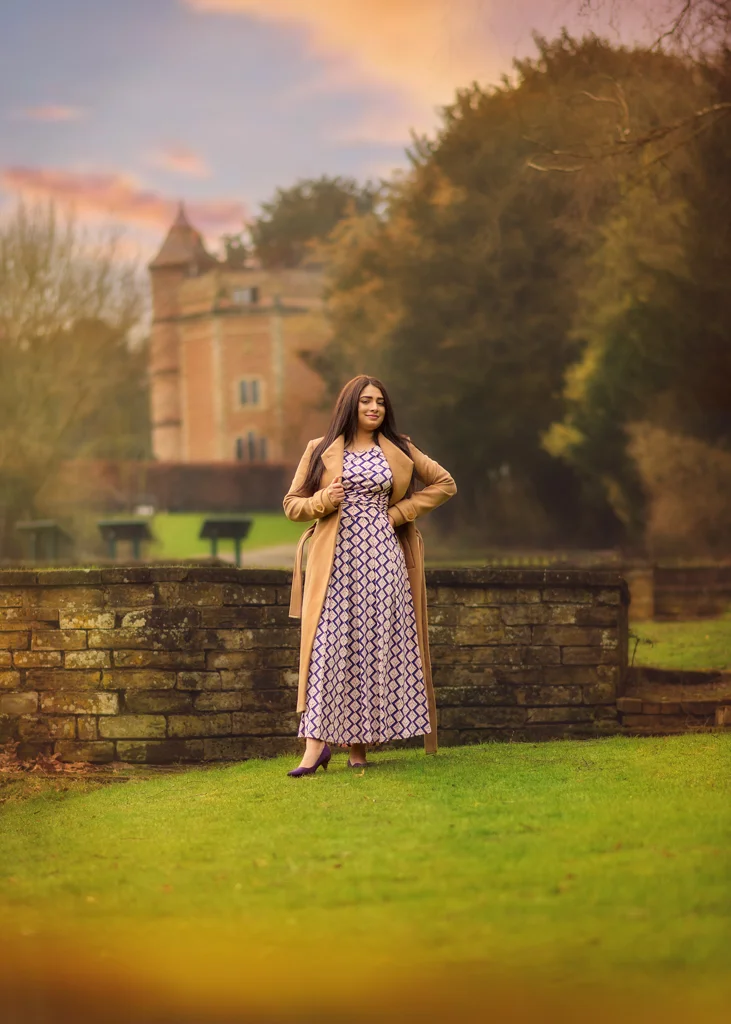 Woman in a long patterned dress posing confidently near a historic building during her outdoor photoshoot for women.