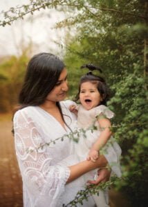 A mother smiles as she holds her laughing baby during a Mother and Child Photoshoot in Nottingham.