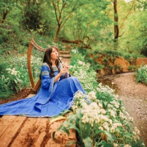 A woman in a vibrant blue dress and embroidered jacket sits by a harp in a lush forest glade, her expression peaceful as she plays, surrounded by wildflowers.