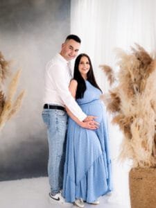 Expectant couple holding the baby bump with the mother in a flowing blue dress during a Nottingham maternity photoshoot.