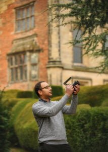 Photographer adjusting camera settings for a business photography session in a historic garden.