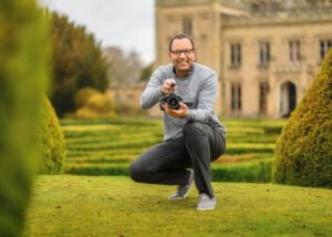 Photographer crouching in a formal garden capturing professional business photography for branding.