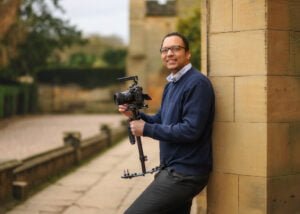 Photographer leaning against a column with professional camera gear for a business photography session.