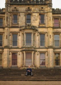Photographer sitting on the steps of a historic building during a business photography session.