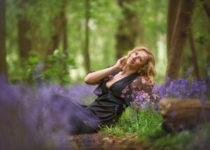 A woman in contemplative repose lies amidst the bluebells of Nottingham, her bluebell photoshoot exuding peace and natural elegance.