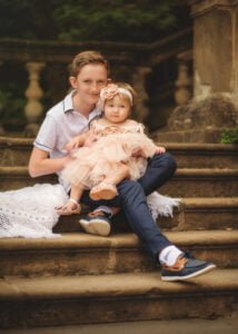 Older brother holding his baby sister during her 1st Birthday Photoshoot on historic stone steps.