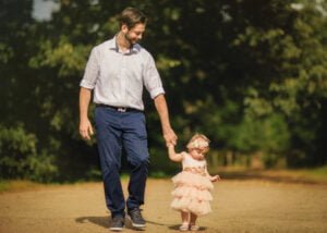 Father walking hand-in-hand with his toddler daughter in a soft pink dress during her 1st Birthday Photoshoot.