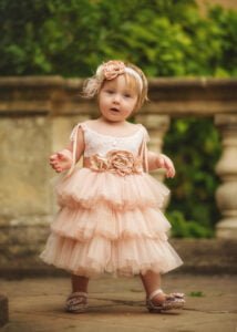 Toddler in a blush pink dress with a floral headband, posing for her 1st Birthday Photoshoot in Nottingham.