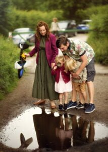Parents and children exploring a puddle together during an outdoor family photoshoot in Nottingham.