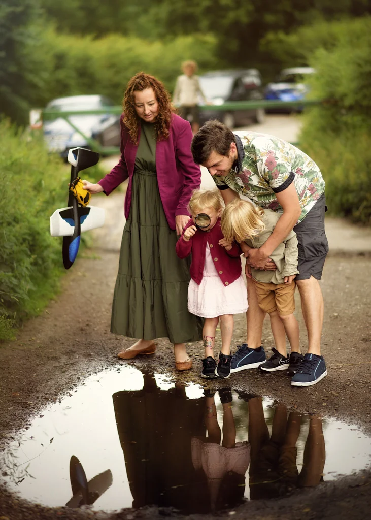 Parents and children exploring a puddle together during an outdoor family photoshoot in Nottingham.