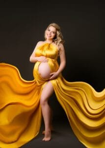 Radiant mom-to-be in a golden flowing maternity gown during a studio baby bump photoshoot in Nottingham.