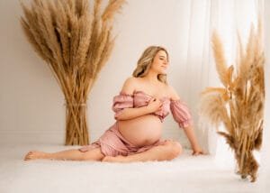 Stylish maternity portrait featuring a mom-to-be in a pink off-the-shoulder dress during a baby bump photoshoot.