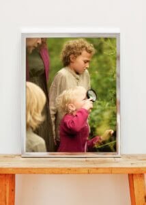 Framed photo of a young girl exploring plants with a magnifying glass during an outdoor family photoshoot in Nottingham.