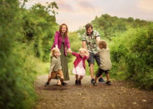 Family holding hands and playing together on a forest path during an outdoor family photoshoot in Nottingham.