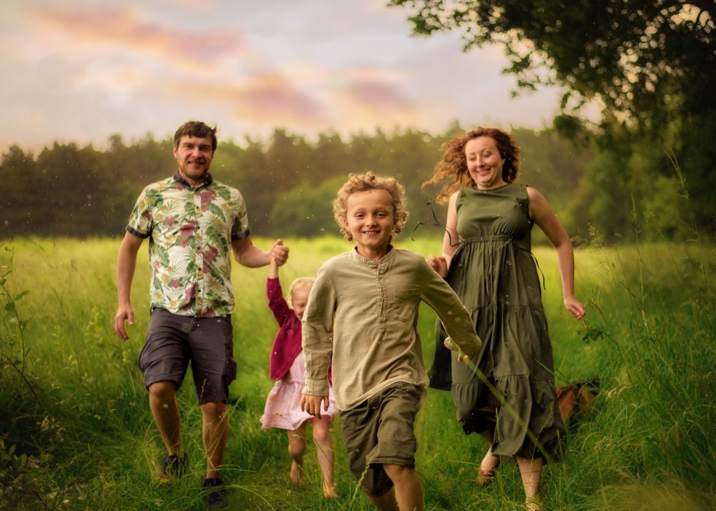 A family runs through a Nottingham field in the twilight, joyfully connected in a spontaneous race against the backdrop of a setting sun.